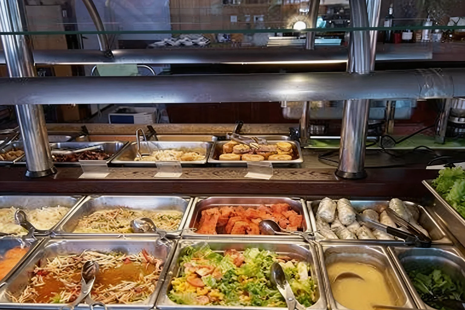 All-you-can-eat counter with hot dishes under a display case