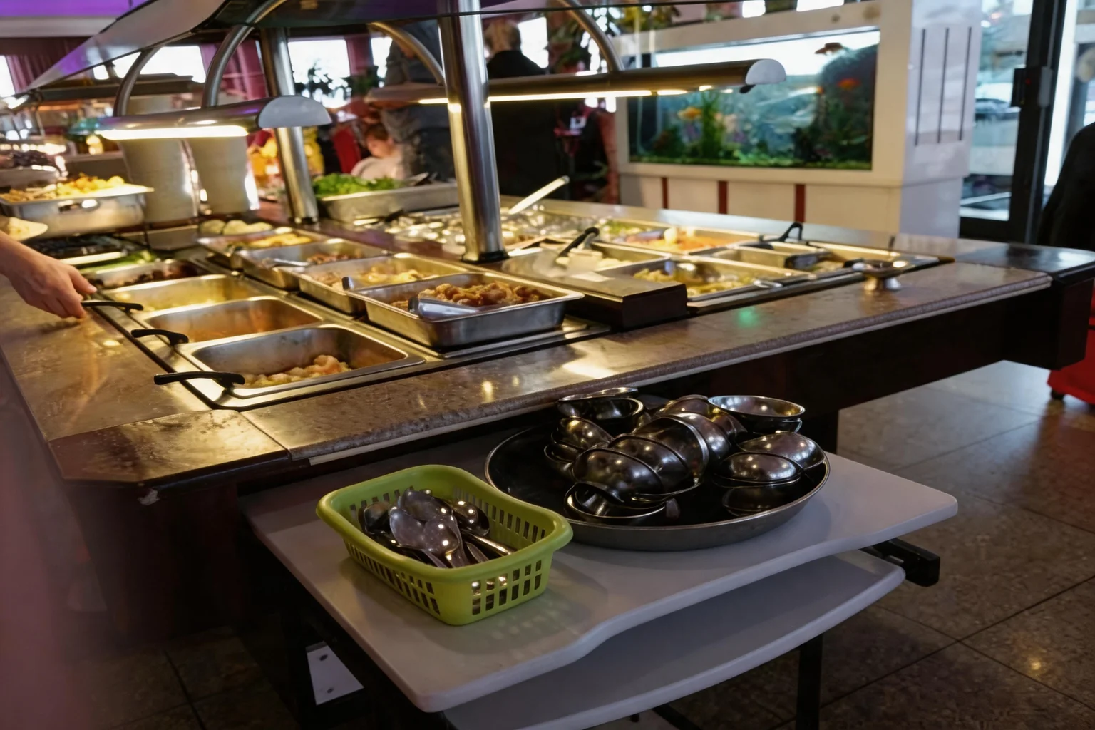 All-you-can-eat counter with hot trays and an aquarium in the background
